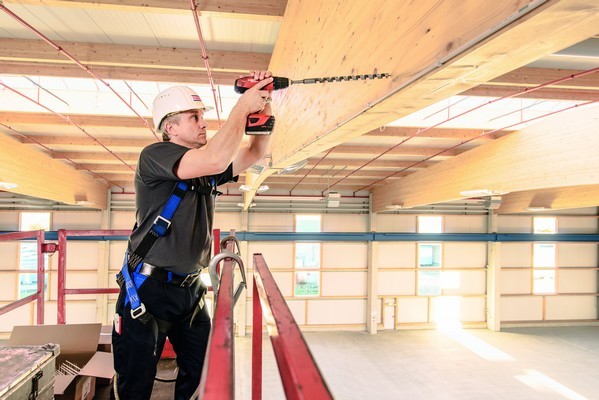 Anwendung Mann mit Bohrmaschine und Schlangenbohrer am Holzbalken